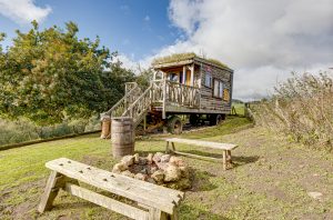 An image of the exterior of our oxo glamping wagon on our farm on Dalby Forest, North Yorkshire. Showing our firepit and seating area outdoors also.